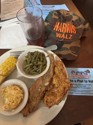 plate of food next to a hat, postcard, and drink