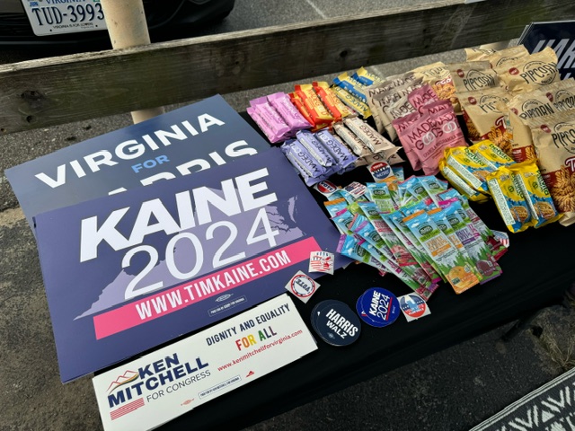 table with bumper stickers, buttons, and snacks on top