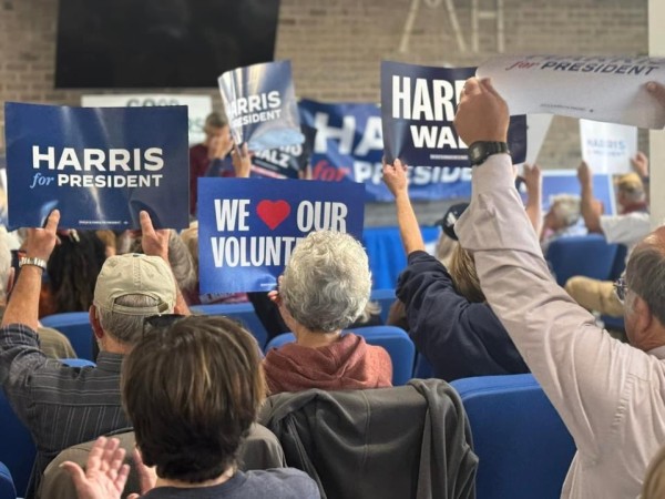 people sitting in chairs holding up Harris signs